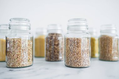 İçinde kinoa pirinç karabuğday kuskusu ve arpa da dahil olmak üzere içinde farklı tahıl türleri bulunan temiz kiler kavanozları, basit doğal sağlıklı bileşenler kavramı.