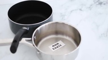 Sağlıklı yemek pişirme ve sert kimyasallar, paslanmaz çelik ve yapışmaz tencereler yan yana, ilkinde Non Toxic etiketli.