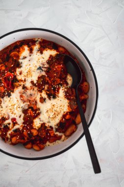 Biberli, sütsüz kremalı, sağlıklı bitkisel yemek tarifleriyle kaplı vegan beyaz fasulyeli shakshuka ve zeytin.