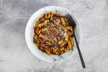 Vejetaryen pesto fusilli makarna, siyah fasulye ve Akdeniz sebzeleriyle karışık tohumlar, sağlıklı bitki temelli yemek tarifleri konsepti.