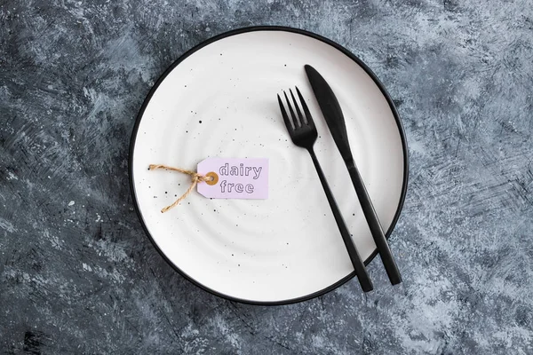 dairy-free product tag on top of dining plate with fork and knife, concept of healthy nutrition and ethical choices