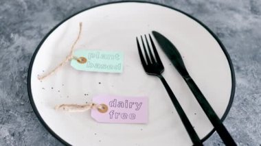 Yemek tabağının tepesinde çatal ve bıçakla bitkisel ve mandırasız ürün etiketi, sağlıklı beslenme kavramı ve etik tercihler