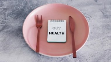 Yemek tabağının üstüne çatal ve bıçakla bağırsak sağlığı metni, sağlıklı beslenme kavramı ve bilimsel araştırma.