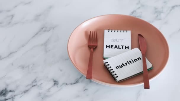 フォークとナイフでダイニングプレートの上にノートパッド上の腸の健康栄養テキスト 健康的な栄養と科学研究の概念 — ストック動画