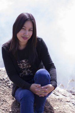 Cliff üzerinde oturan sırt çantası ile Taylandlı kadın