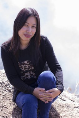 Cliff üzerinde oturan sırt çantası ile Taylandlı kadın