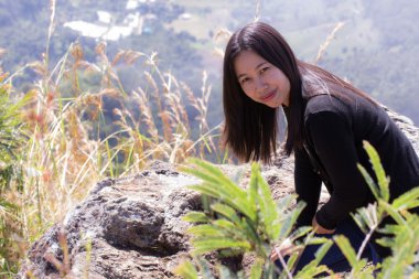 Cliff üzerinde oturan sırt çantası ile Taylandlı kadın