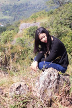 Cliff üzerinde oturan sırt çantası ile Taylandlı kadın