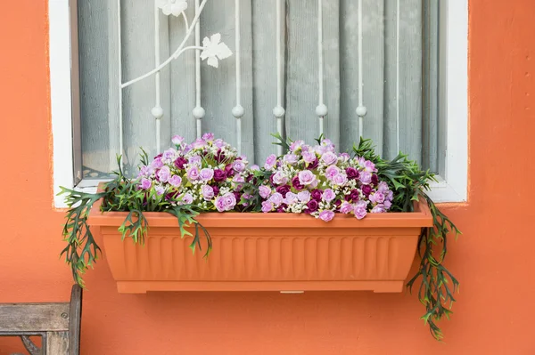 Fönster med konstgjorda blommor i korg — Stockfoto