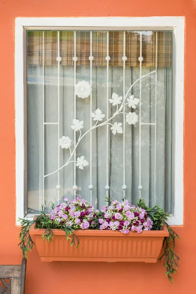 Fönster med konstgjorda blommor i korg — Stockfoto