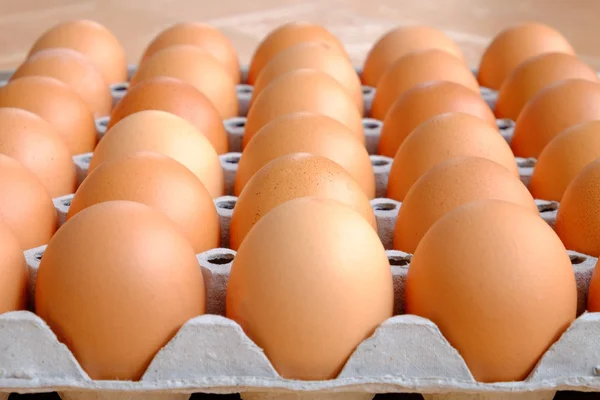 A dozen brown eggs in a carton on a wooden table — Stock Photo, Image