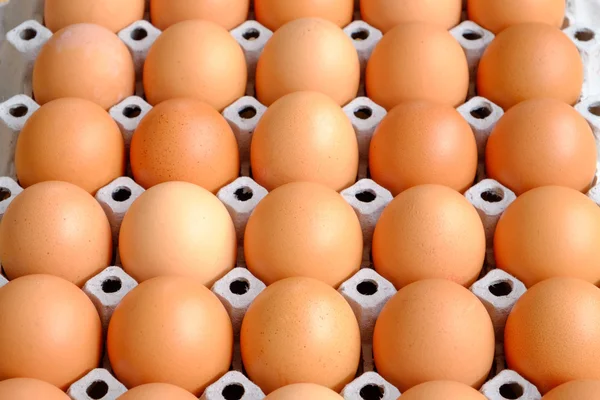 A dozen brown eggs in a carton on a wooden table — Stock Photo, Image