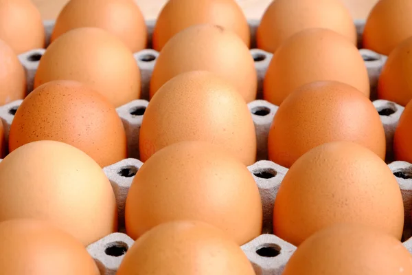 Uma dúzia de ovos marrons em uma caixa em uma mesa de madeira — Fotografia de Stock