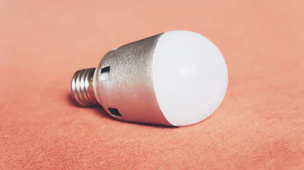 Light bulb on a soft fluffy peach-colored background