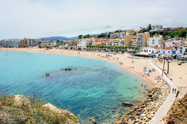 Turistler, İspanya 'nın güzel bir yaz gününde Costa Brava' nın Blanes plajında eğleniyorlar.