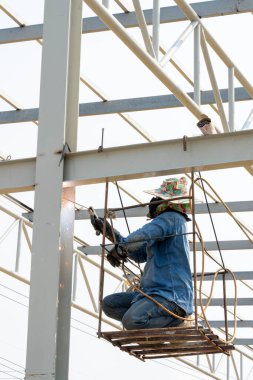 Elektrikli kaynak kablosu kullanarak bir metali kesen bir kaynakçı..