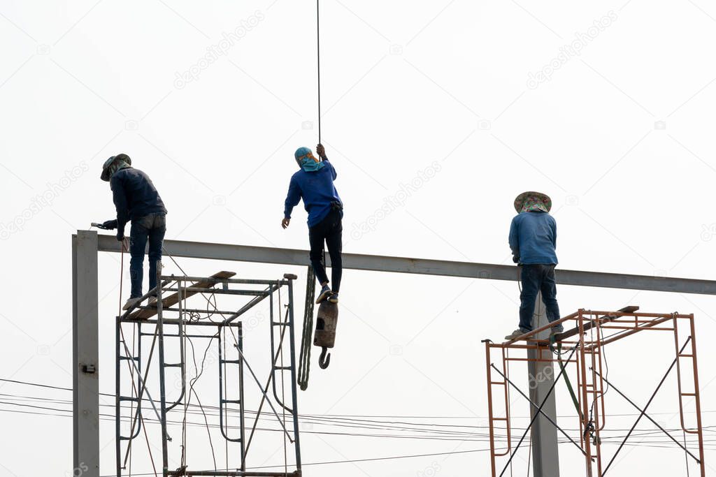 A worker swing and hang Still Beams Crane and Worker conect the steel beam with the srell pole..Worker conect the steel beam by gas welding equipment