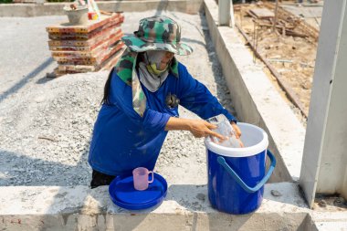 Bayan inşaattaki Mavi Plastik buz kutusuna ve pembe plastiğe buz koydu..