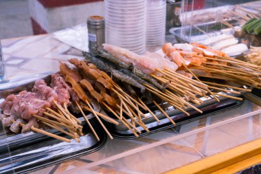 Müşteri, şişle taze olarak sipariş edilecek yiyecekleri seçebilir. Ahşap ızgara yemek kesme havası karşılama, barbekü, domuz barbeküsü, ızgara kalamar, tezgahın tepesini kaldırarak. Tayland sokak yiyecekleri barbekü şişleri, Tayland tarifi.