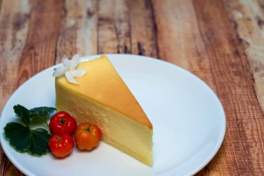 Kırmızı böğürtlenli küçük beyaz tabakta peynirli kekin yüksek açılı görüntüsü.