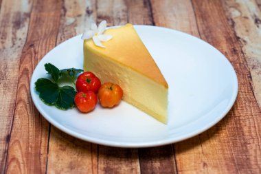 Kırmızı böğürtlenli küçük beyaz tabakta peynirli kekin yüksek açılı görüntüsü.