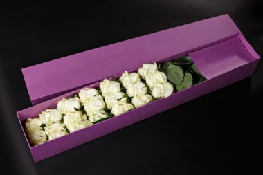 White roses in gift purple souvenir box, place the logo on a bla