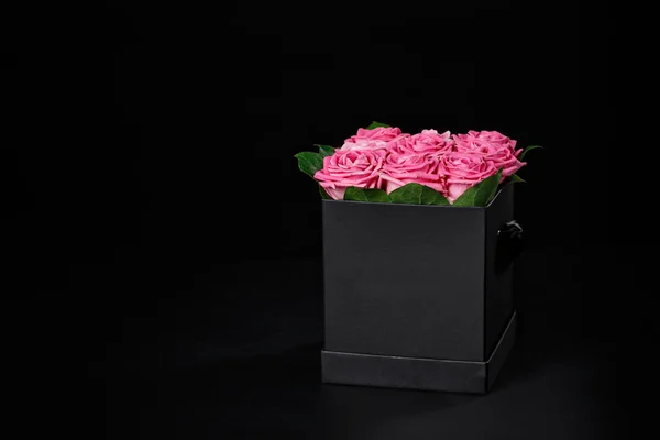 Rose rosa in una piccola scatola regalo quadrata nera su un backgroun nero — Foto Stock