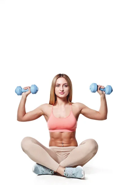 Hermosa joven con un cuerpo deportivo con mancuernas en un fondo de estudio blanco — Foto de Stock