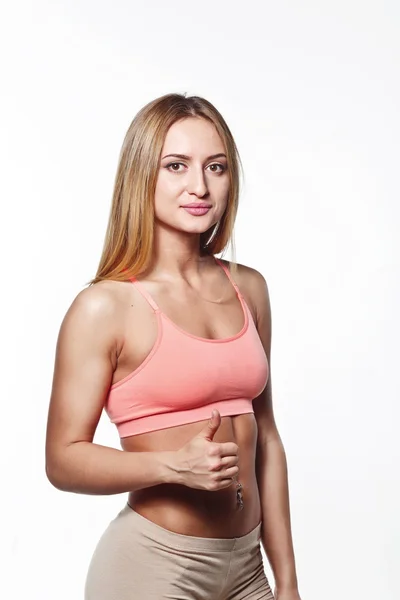 Attractive athletic young girl holding up a finger, with piercing on a white studio background — Stockfoto