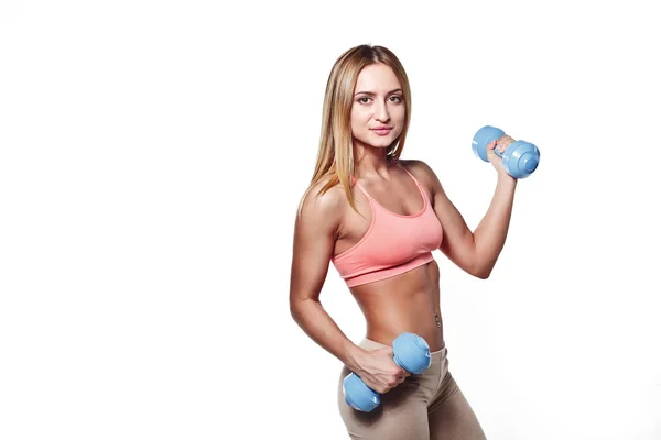 Hermosa joven con un cuerpo deportivo con mancuernas en un fondo de estudio blanco — Foto de Stock