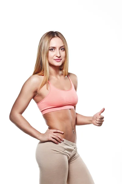 Attractive athletic young girl holding up a finger, with piercing on a white studio background — Stock fotografie