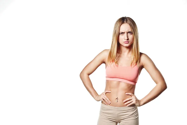 Hermosa joven con un cuerpo deportivo, sobre fondo de estudio blanco, con la emoción del mal — Foto de Stock