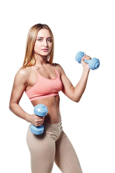 Beautiful young girl with a sports body with dumbbells on a white studio background — Stok fotoğraf