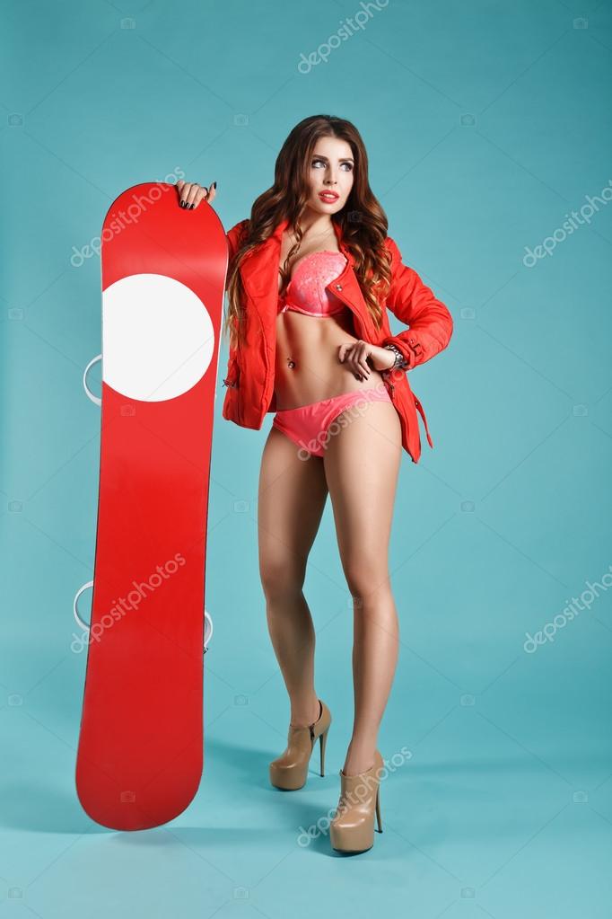 Attractive Young Sexy Girl in Bikini Holding Red Snowboard On Winter Background. Space For Your logo. Studio Photography. Ideal for Advertisment