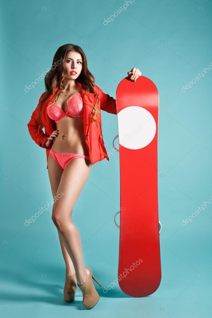 Attractive Young Sexy Girl in Bikini Holding Red Snowboard On Winter Background. Space For Your logo. Studio Photography. Ideal for Advertisment