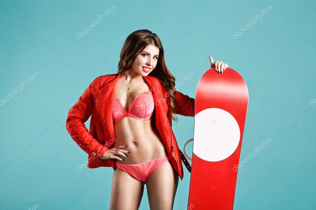 Pretty Fitness Smiling Young Woman With Nice Makeup Holding Red Snowboard On Winter Background. Space For Your logo. Studio Photography. Ideal for Advertisment