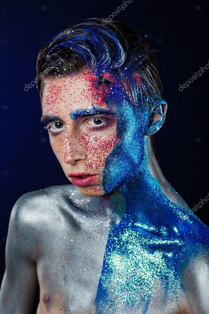 Crazy young androgyne man with face art. SPACEMAN. Freak person. Sperm on face. Tinsel creative blue makeup. Intersex and anorexia concept. Space for logo