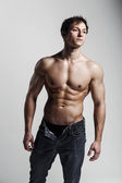 Muscular male model bodybuilder with unbuttoned jeans. Studio sh