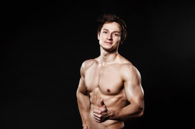 Yakışıklı atletik adam siyah pantolonla başparmak-up gösteren. Güçlü bo