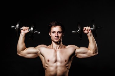 Handsome athletic man with dumbbells confidently looking forward