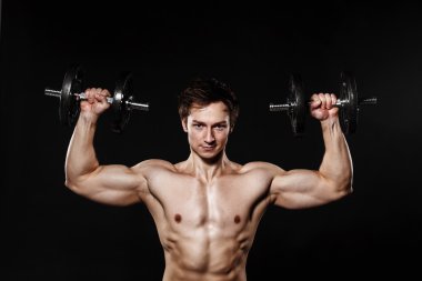 Handsome athletic man with dumbbells confidently looking forward