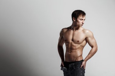 Yakışıklı atletik adam düğmesiz kot ile yan bakıyor. Stron