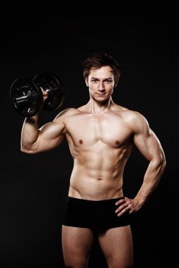 Handsome athletic man with dumbbells confidently looking forward
