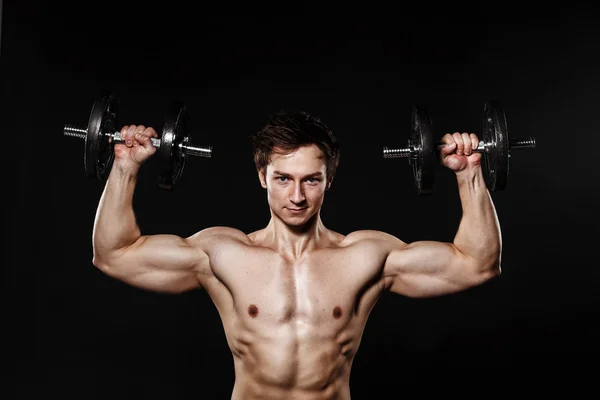 Handsome athletic man with dumbbells confidently looking forward — Stock Fotó
