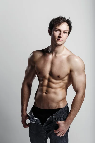 Muscular modelo masculino fisiculturista com jeans desabotoado. Estúdio — Fotografia de Stock