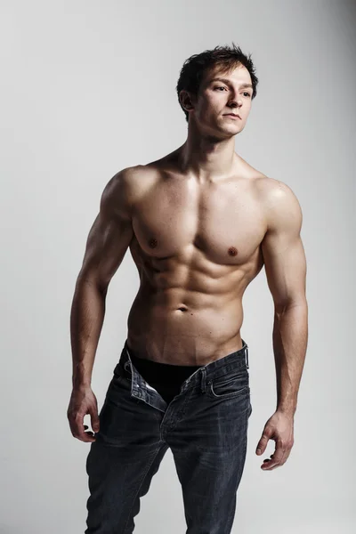 Muscular male model bodybuilder with unbuttoned jeans. Studio sh — Stock Photo, Image