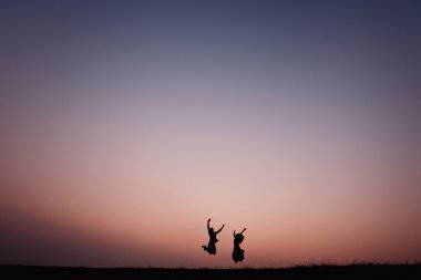 Siluet açık havada günbatımında dramatik atlama genç Çift 