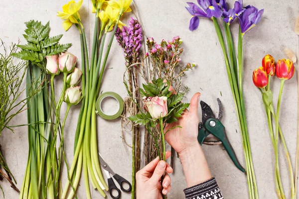 Руки флориста, делающего букет весенних цветов — стоковое фото