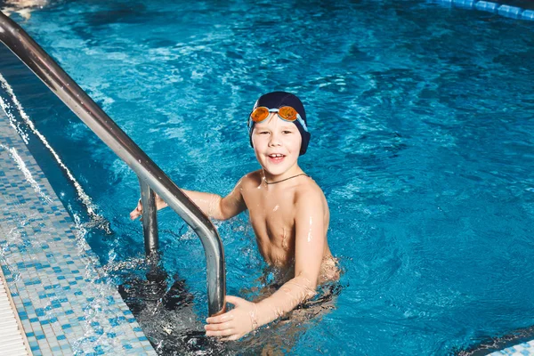 Young boy using ladder to exit swimming pool Stock Picture