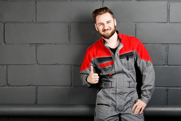 Porträt eines lächelnden Mannes in Overalls nahe Ziegelmauer — Stockfoto